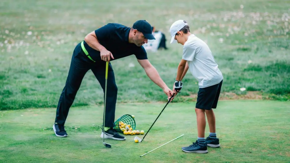 a golf instructor giving instructions to a boy who is learning golf 